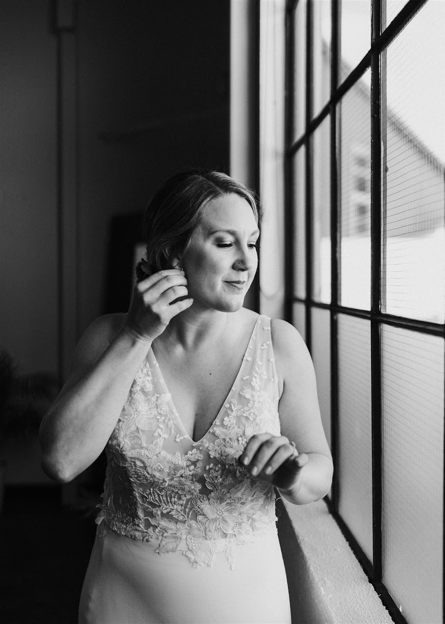 bride fixing her earring while looking out the window. 