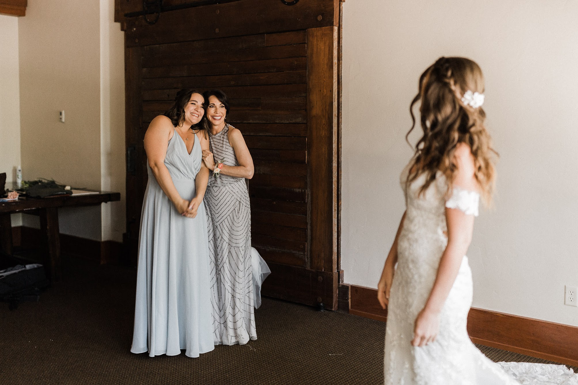 Bride showing off her dress to mother of bride and a bridesmaid 