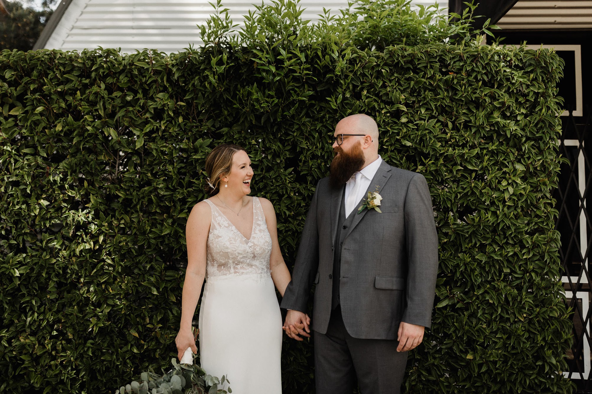 Couple holding hands on their wedding day laughing at each other