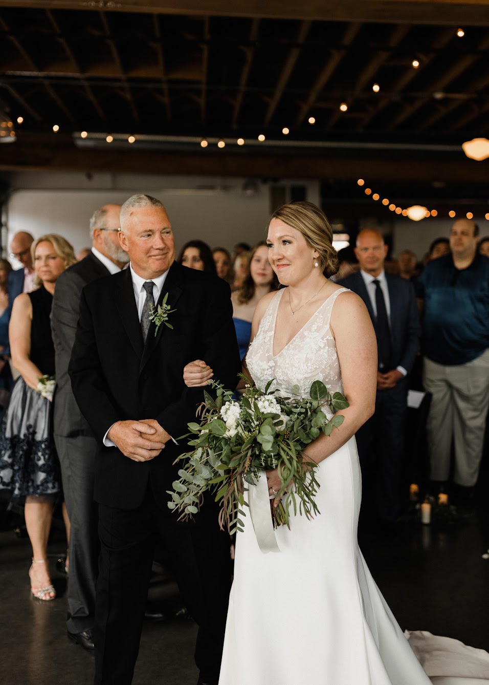 the bride walking down the aisle with her dad as she holds her bridal bouquet