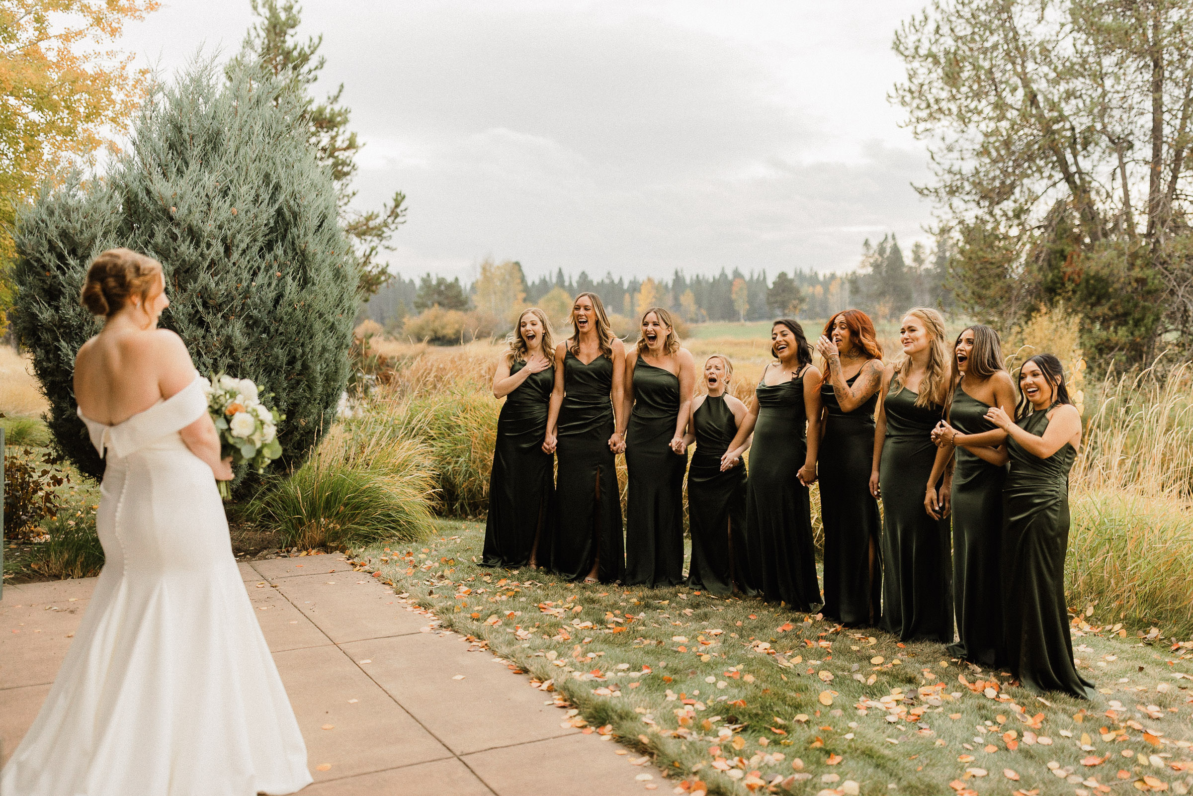 Bridesmaids react enthusiastically as they see bride in her dress for the first time