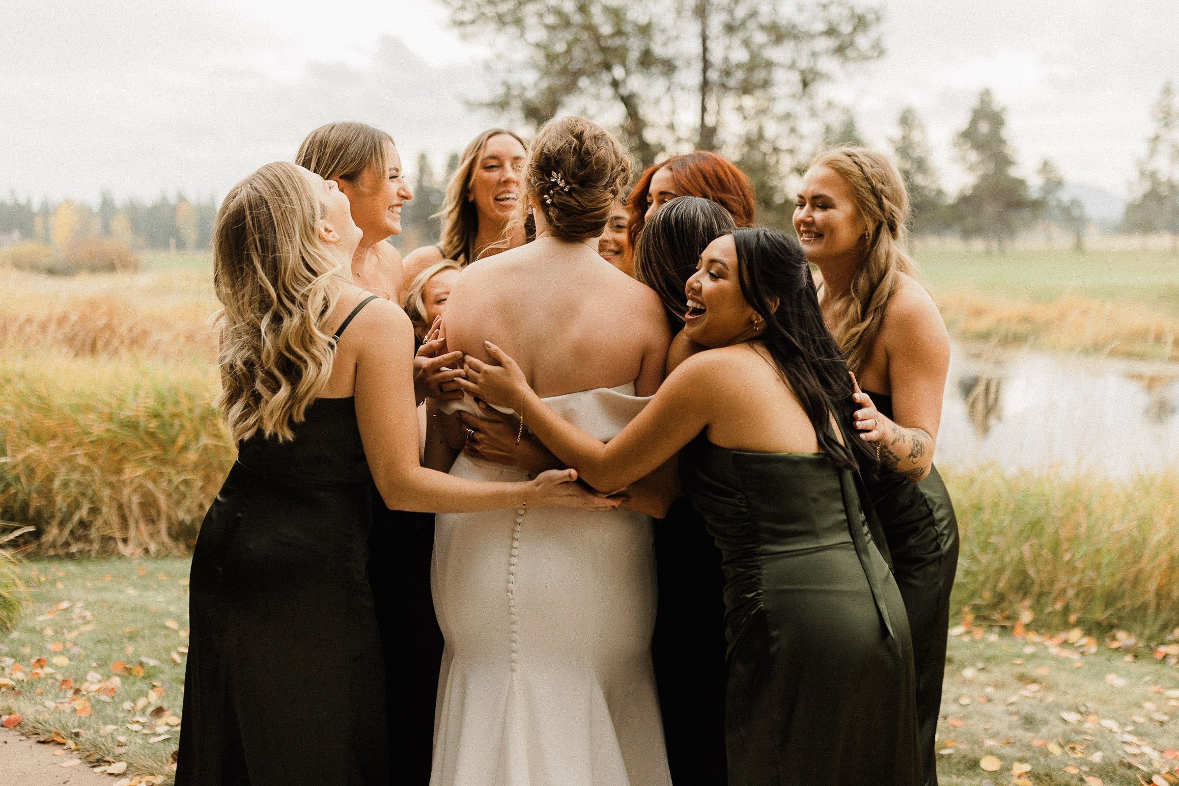 Bridesmaids embrace bride in a group hug