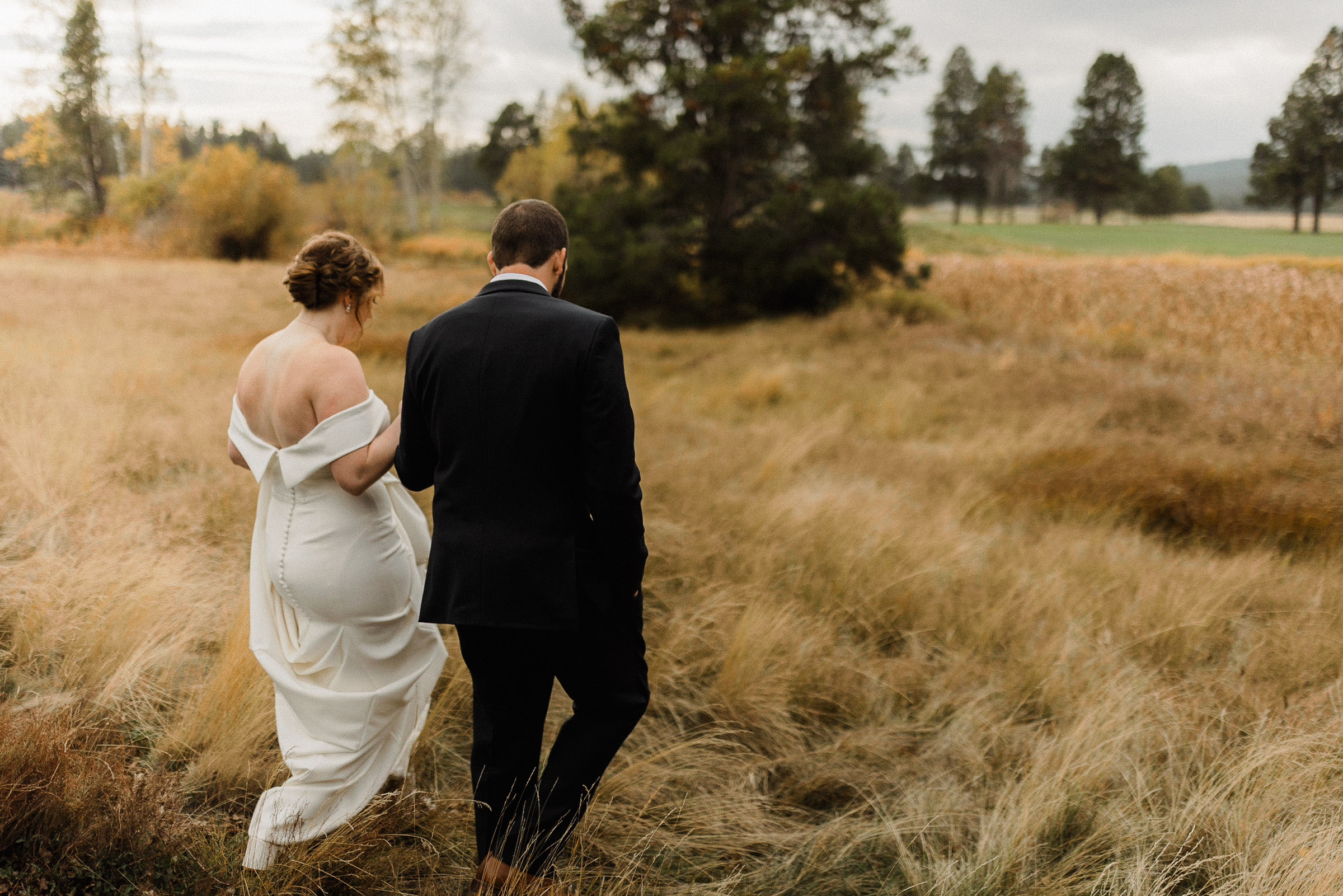 Bride and groom hold hands as they walk into a field at Sunriver Resort
