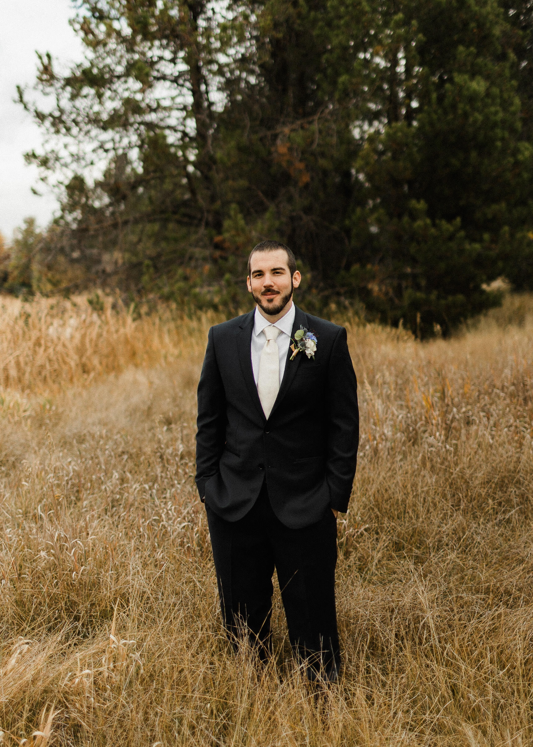 Groom poses for portraits in a field at Sunriver Resort