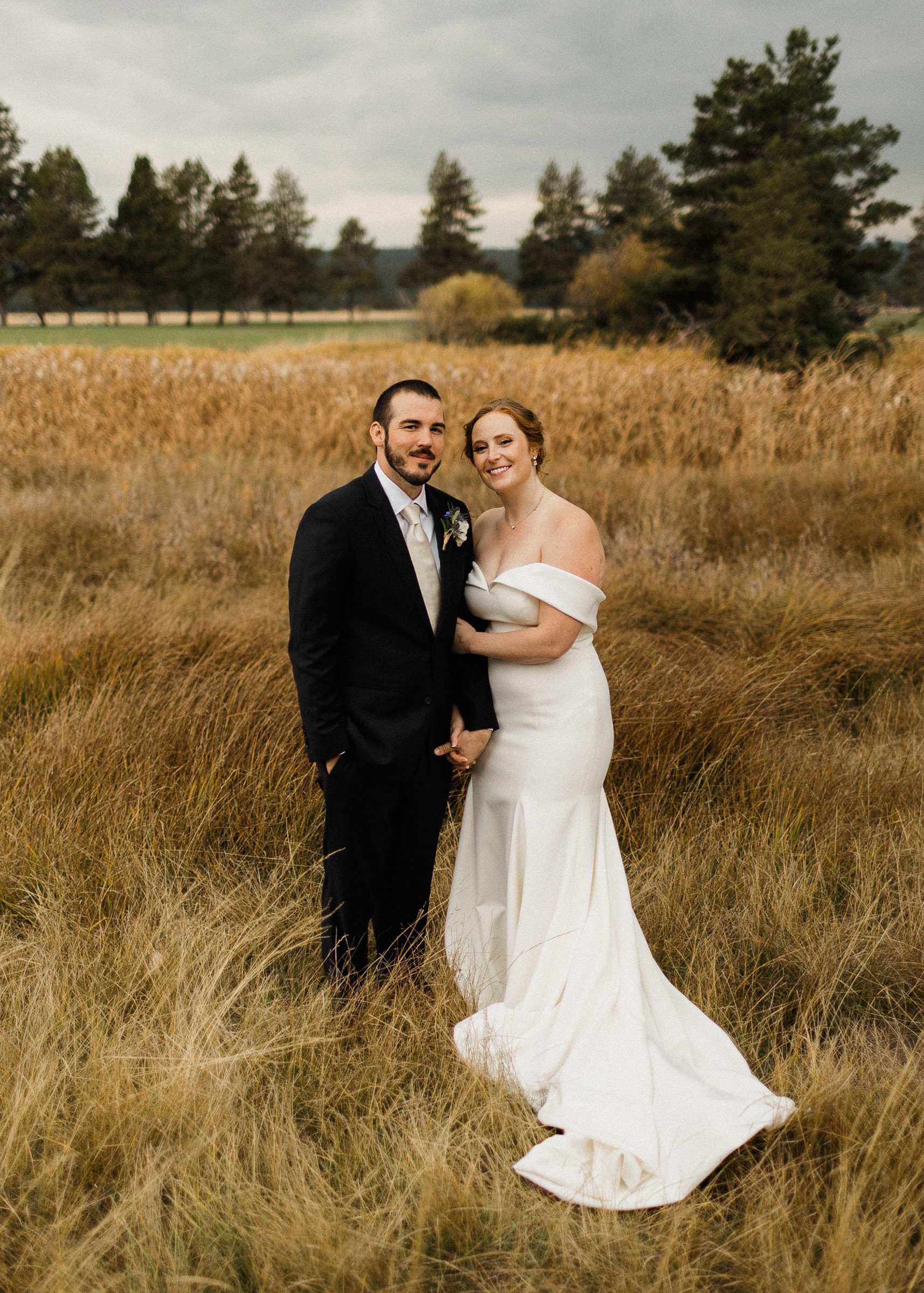 Bride and groom pose for portraits in a field at Sunriver Resort