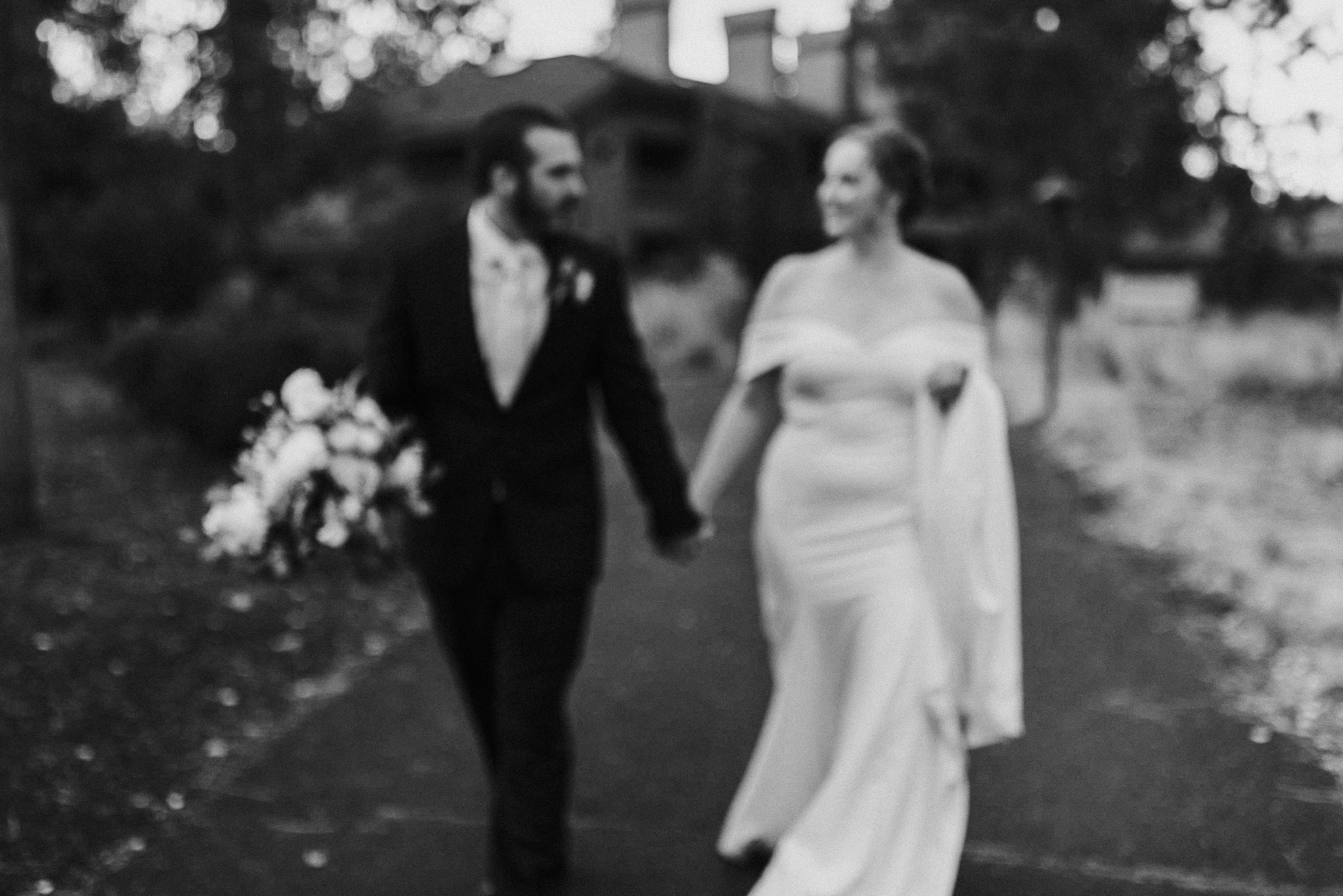 Bride and groom hold hands as they walk down a path