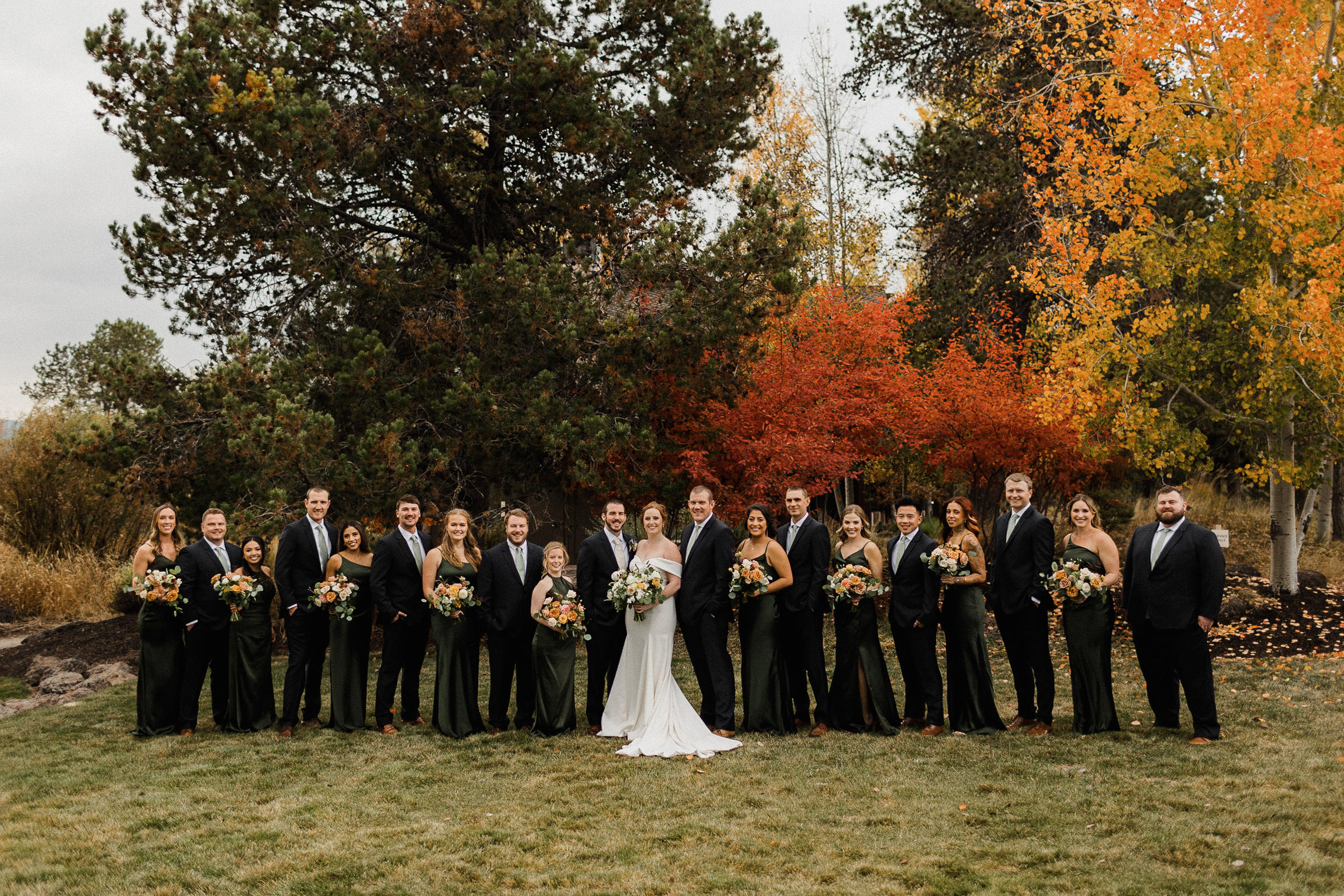 Wedding party poses for a portrait in front of fall foliage