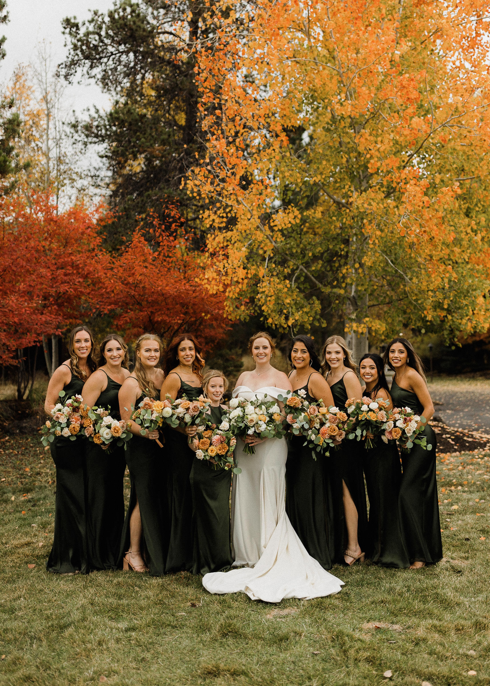 Bridal party poses for a portrait in front of fall foliage