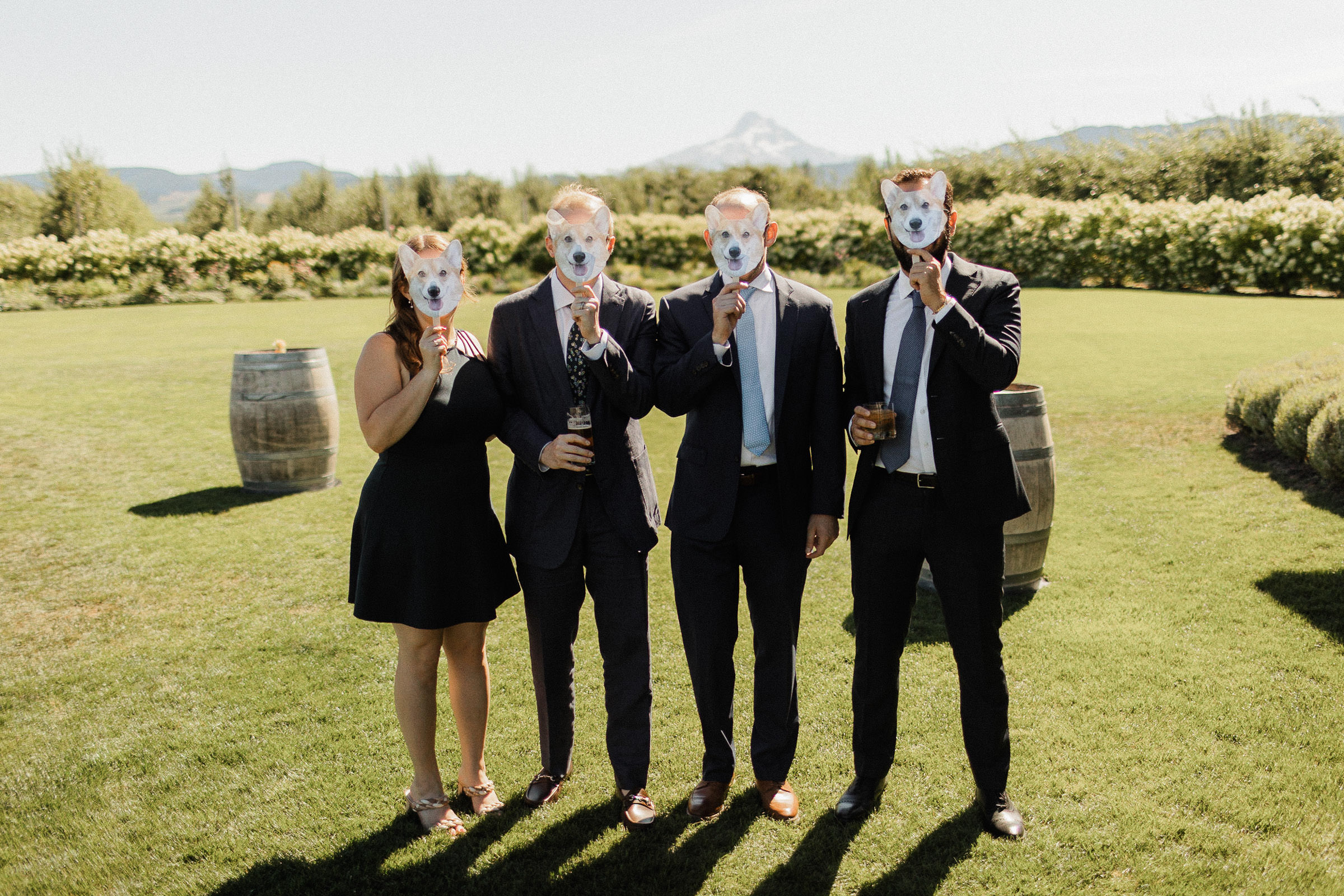 Wedding guests pose using hand fans depicting a corgi face as masks