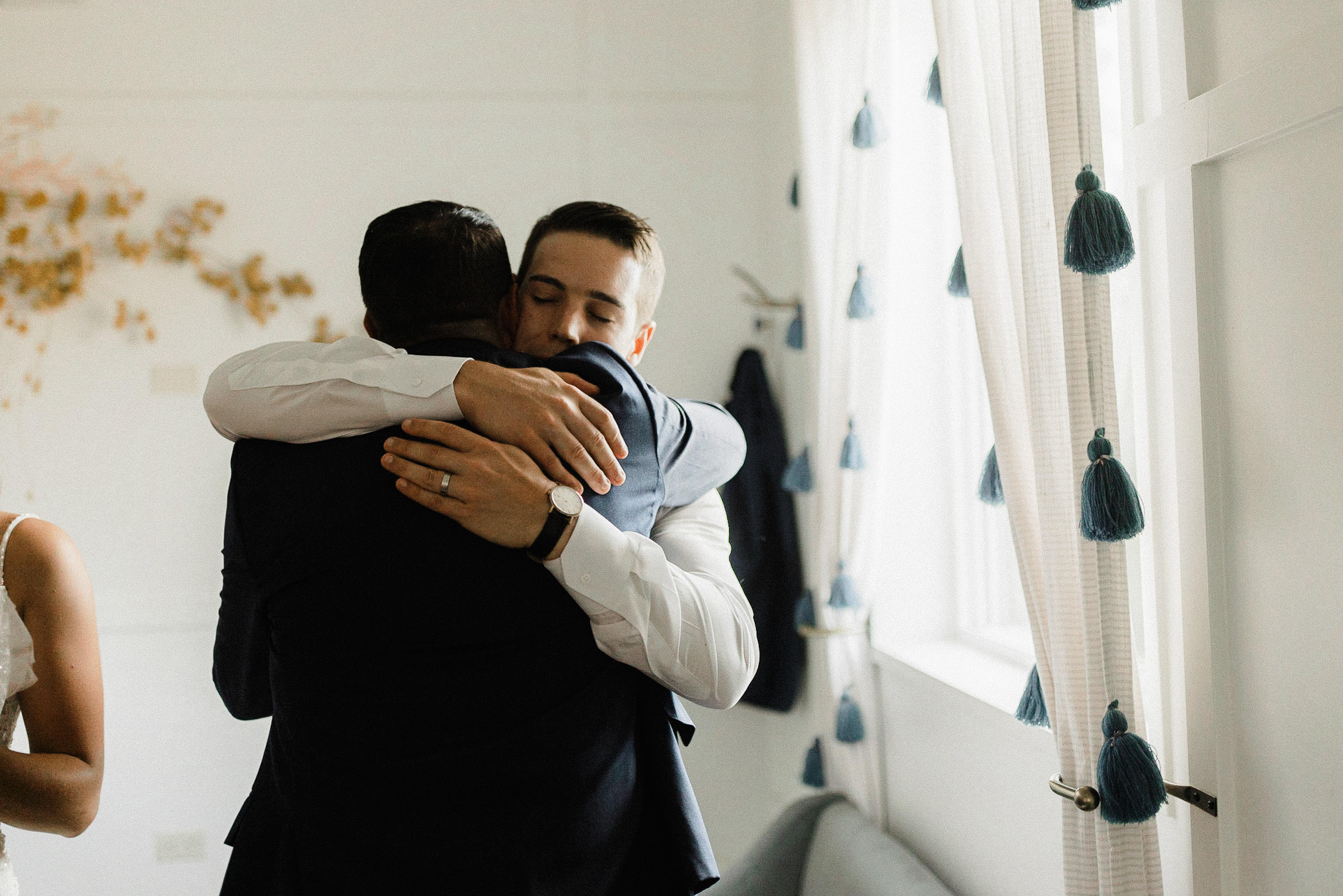 Groom and best man embrace in the bridal suite