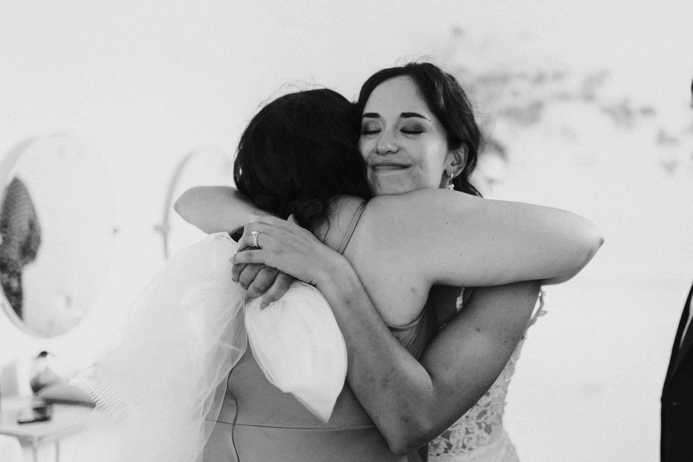 Bride and maid of honor embrace in the bridal suite