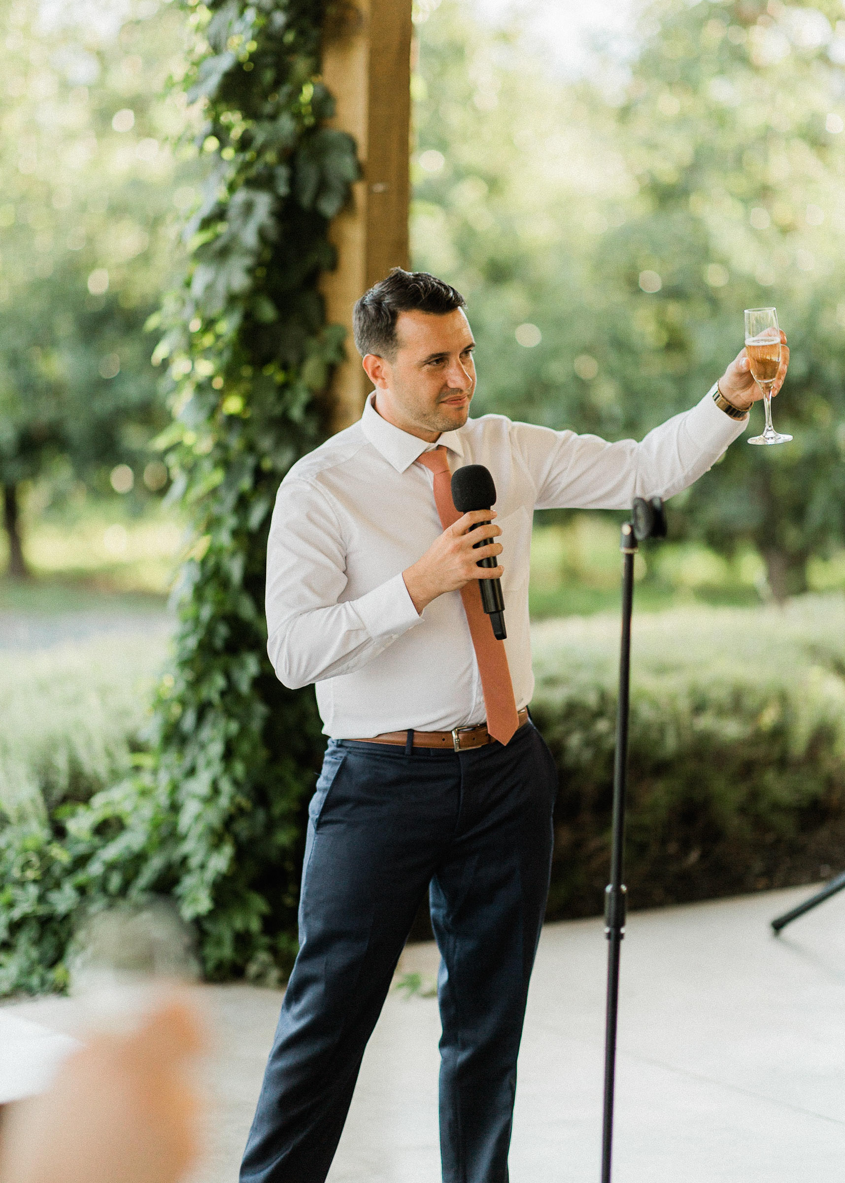 Best man raises a glass of champagne as he gives a toast