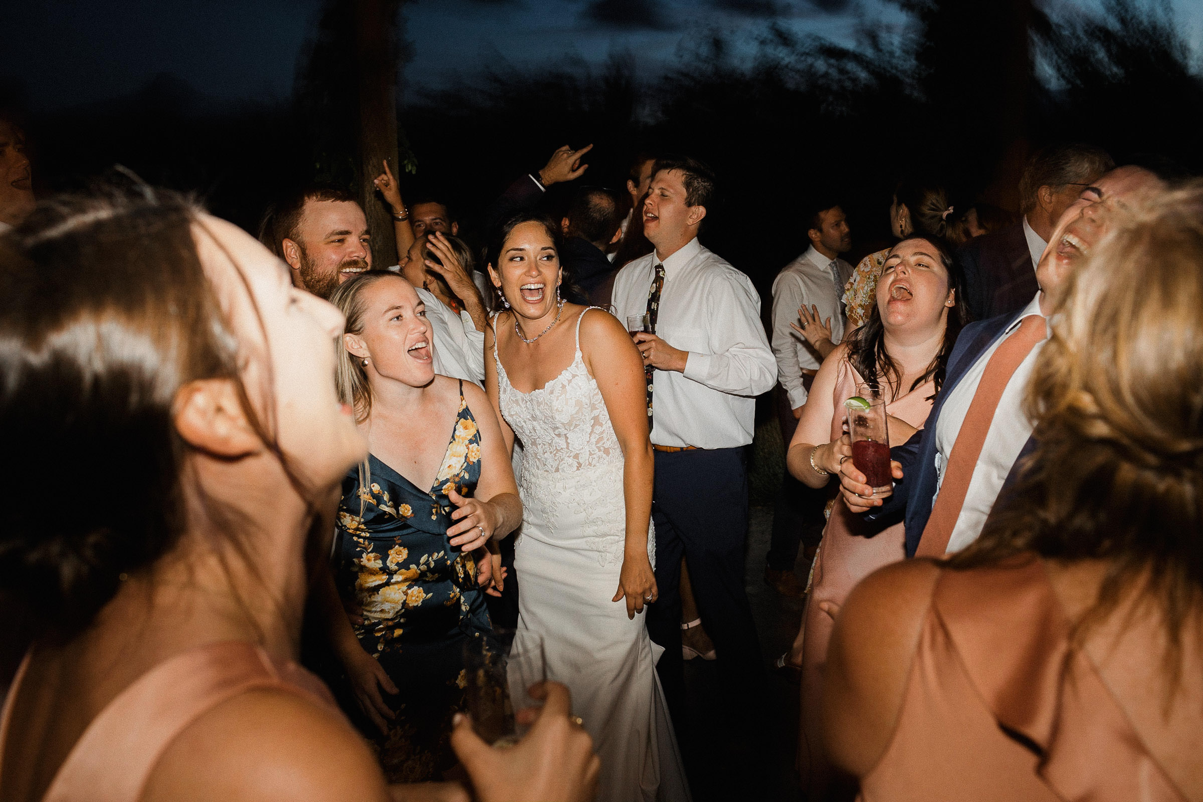 Bride and guests sing along to a song on the dance floor