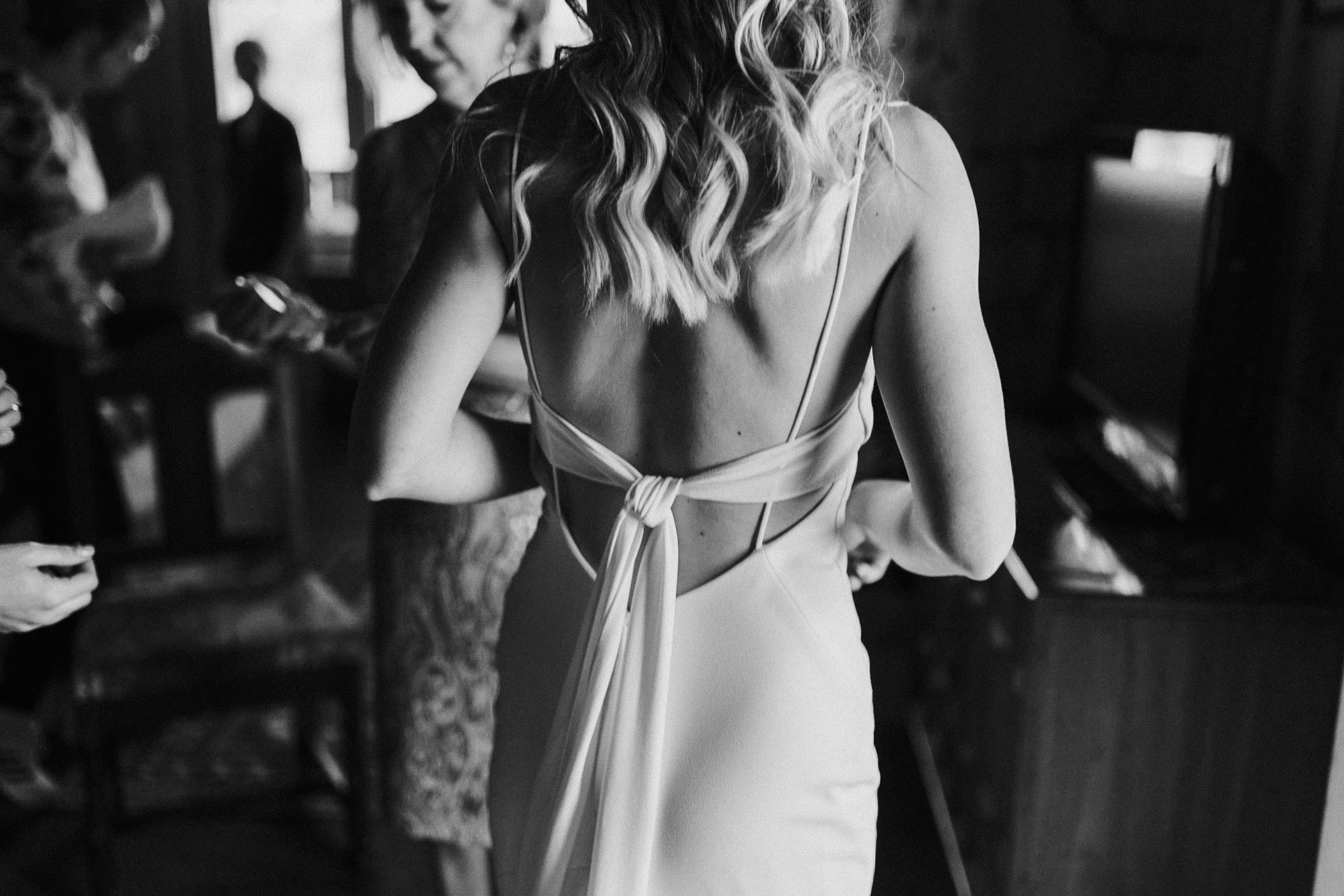 A view of the back of the bride's dress as she gets ready