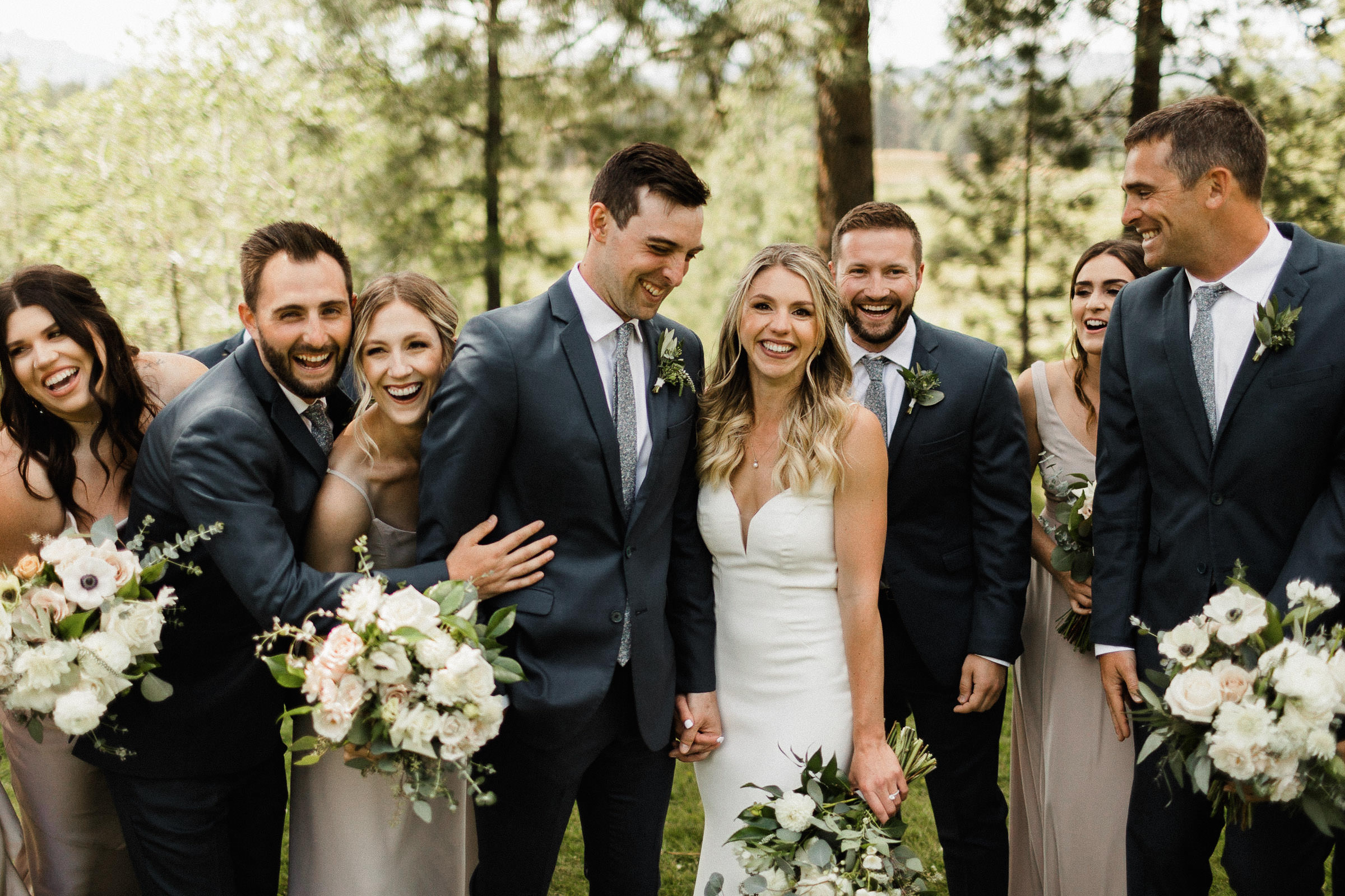 Bride and groom are surrounded by their bridesmaids and groomsmen, all laughing
