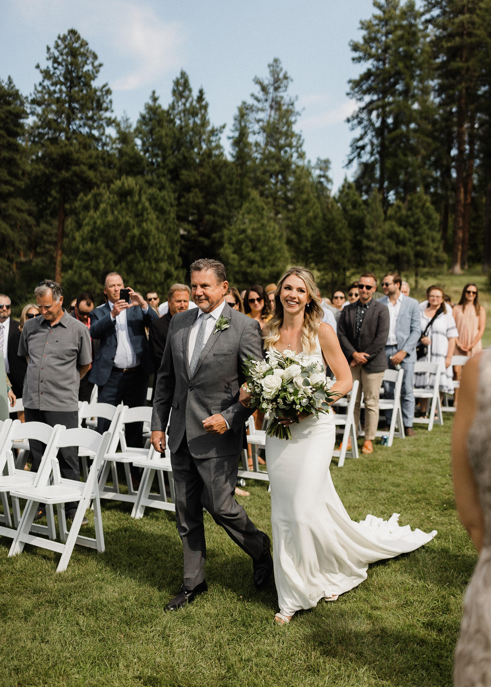 Bride's father walks her down the aisle in a grassy field