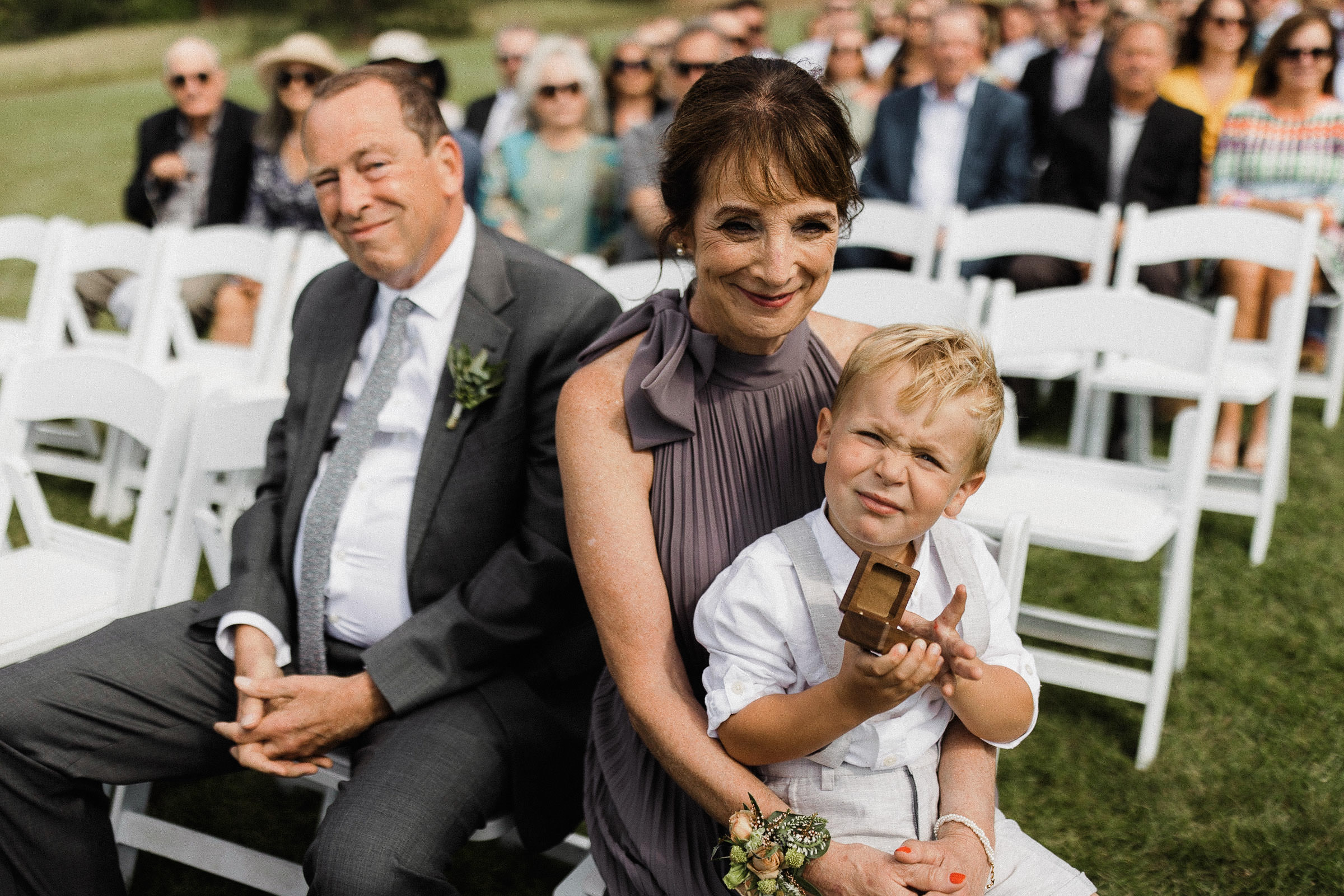 Groom's mom, dad, and nephew smile during ceremony