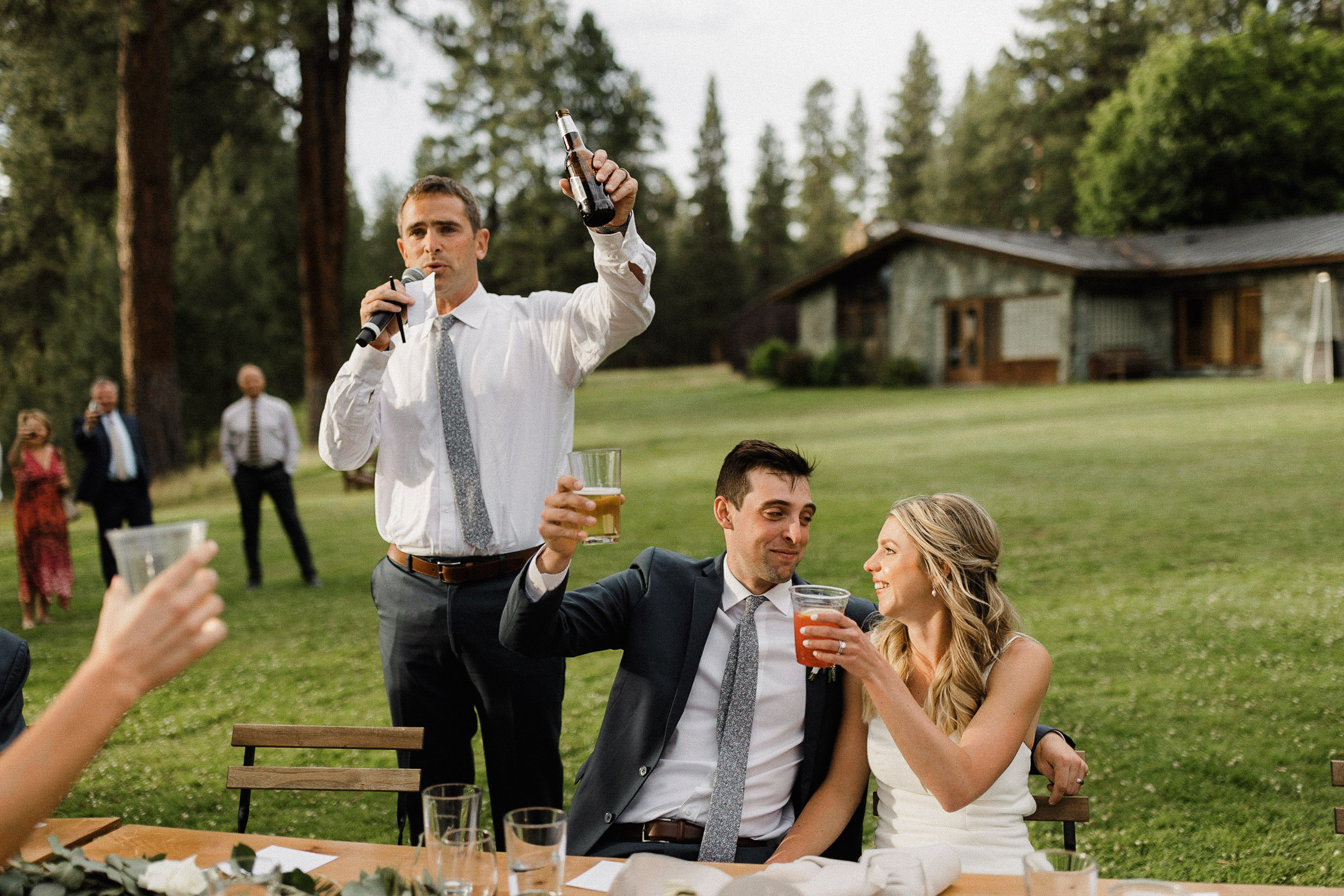 Bride and groom raise their glasses as the groom's brother concludes his toast