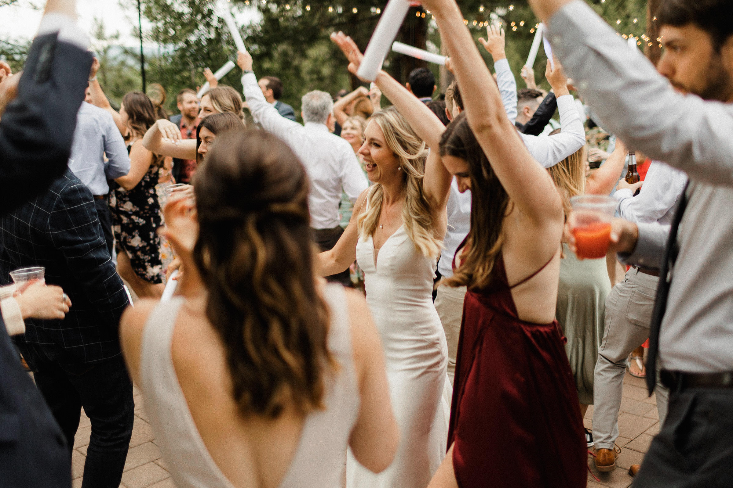 Bride dances with guests, many of them waving foam-covered glow sticks