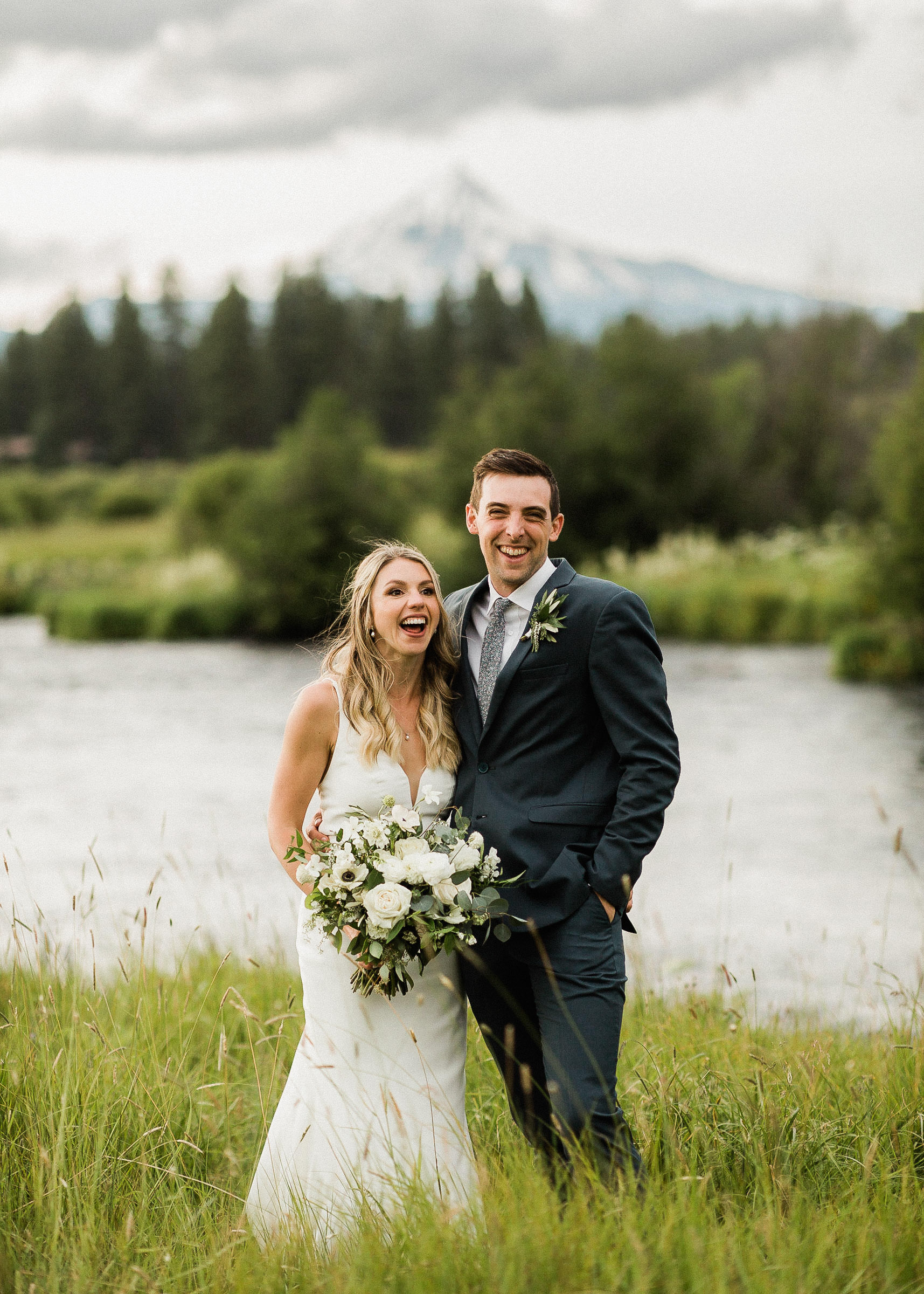 Bride and groom laugh in front of the Metolius River