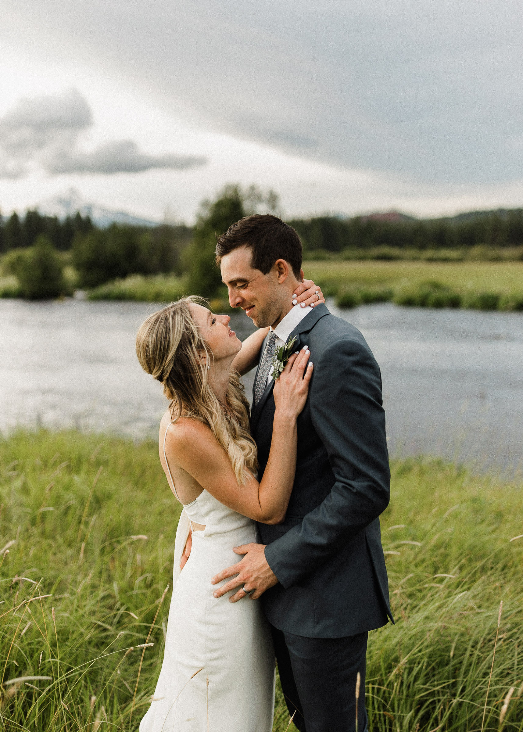 Bride and groom embrace in front of the Metolius River 