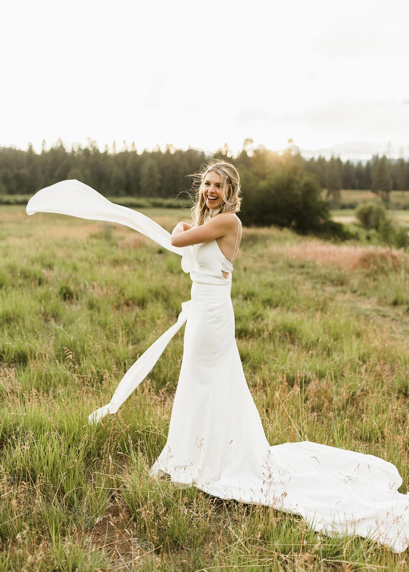 Bride smiles as she tosses the "tails" of her dress into the air 