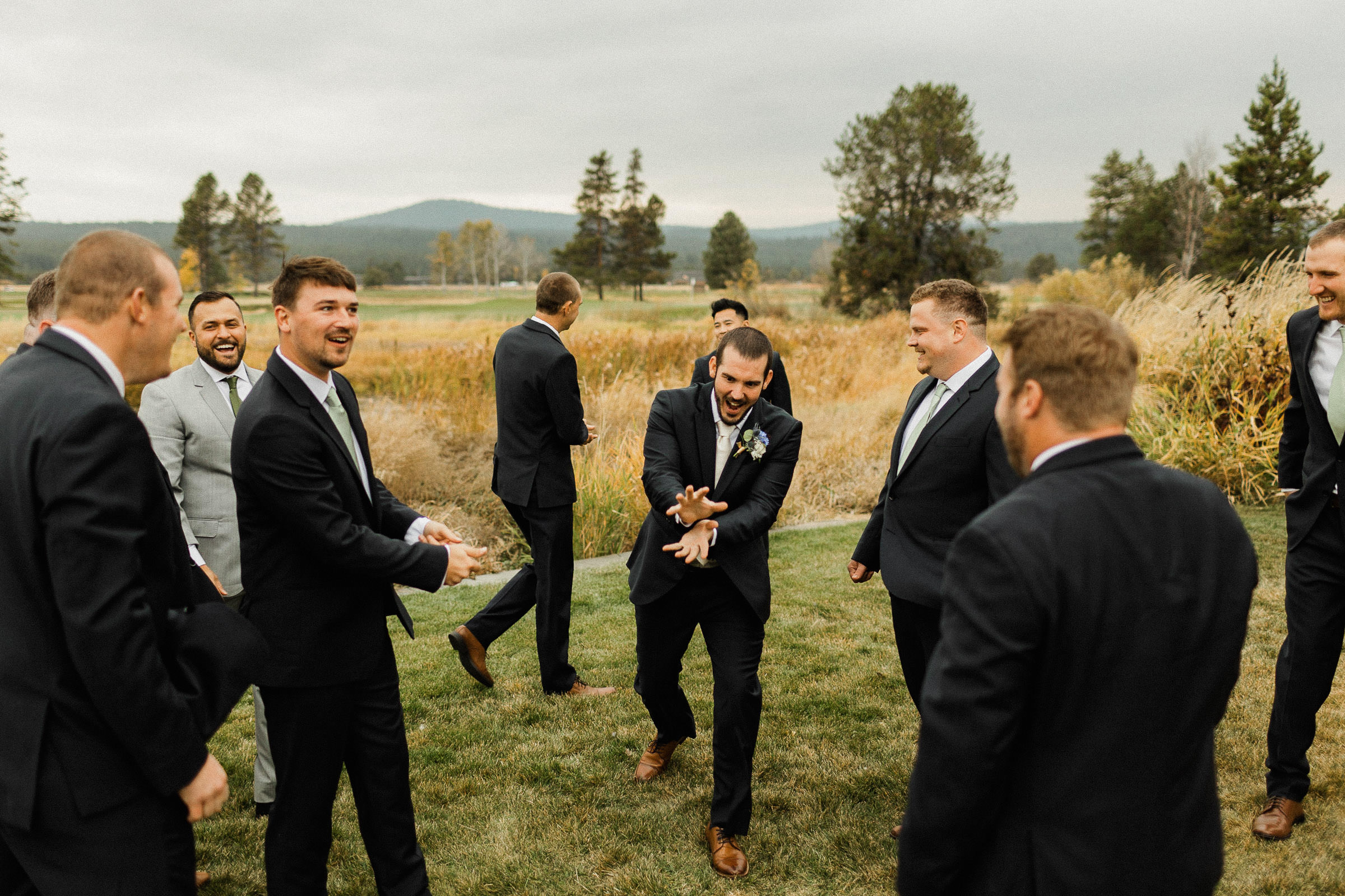 Groom and groomsmen gather and laugh on a lawn at Sunriver Resort