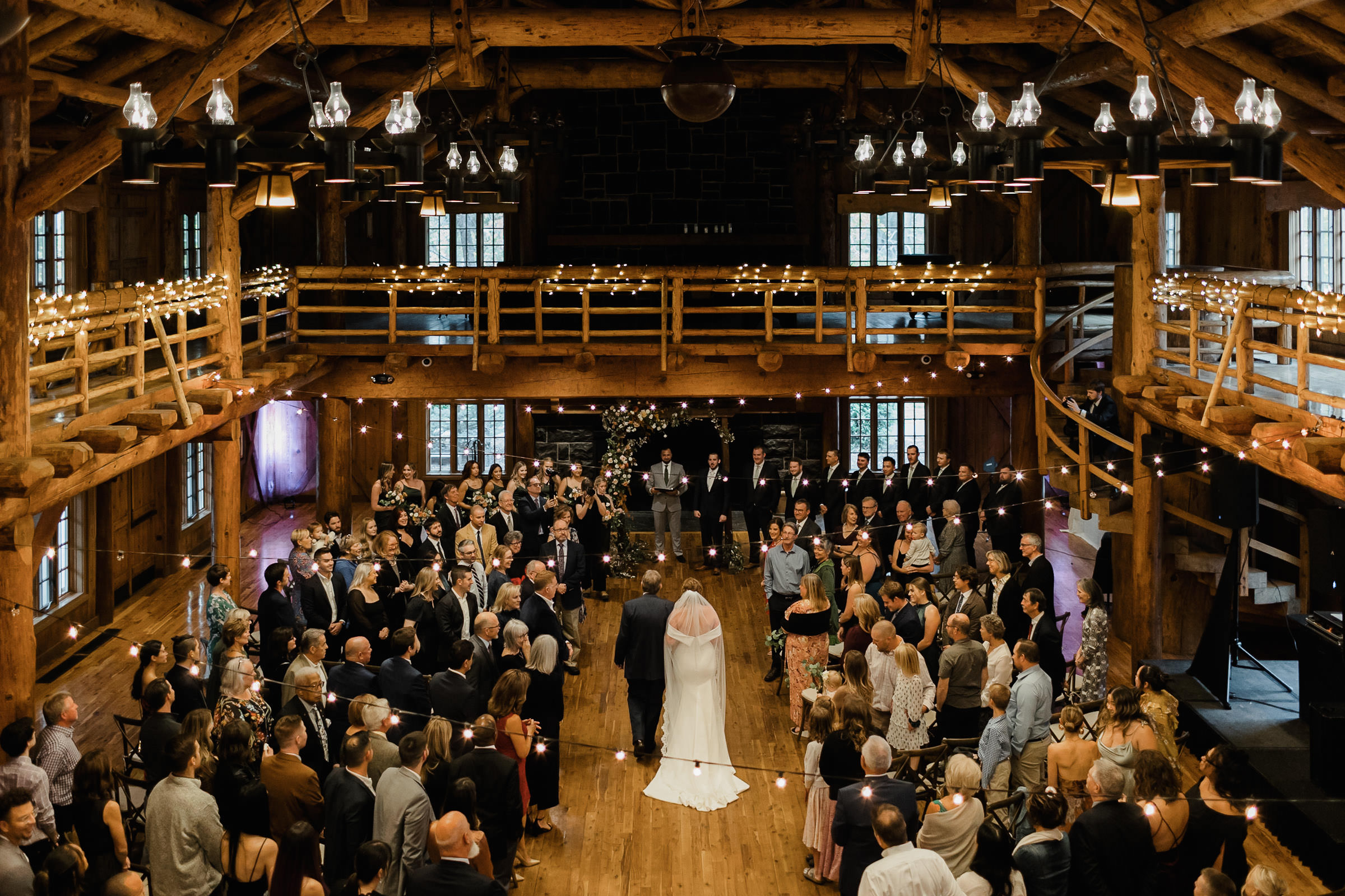 The bride and her father walk down the aisle during a wedding ceremony at Sunriver Resort's Great Hall